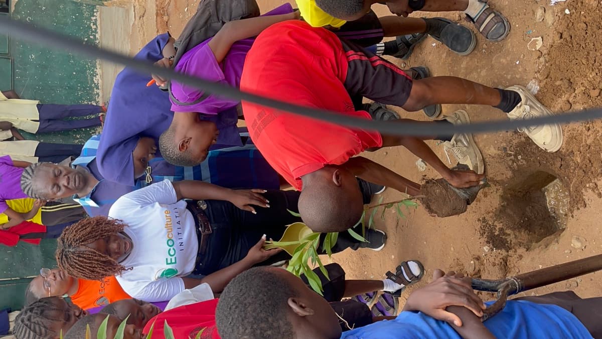 EcoCulture member and children planting a tree
